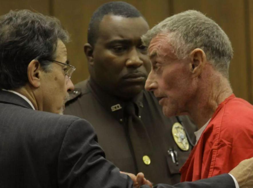 Michael in an orange jumpsuit, talking to his lawyer during the court hearing.