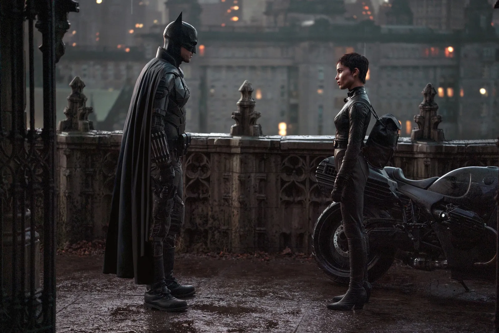 Catwoman and Batman facing eachother at a rooftop talking. There is a motorcycle behind Catwoman.