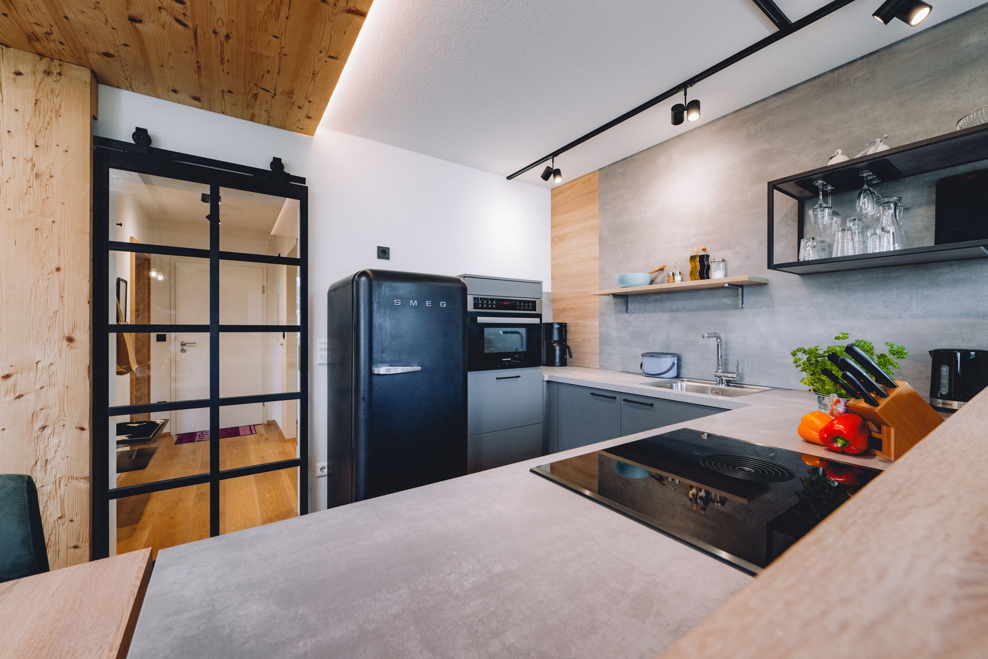 Eine modern eingerichtete Küche mit Blick auf den Flur durch eine Glastür.