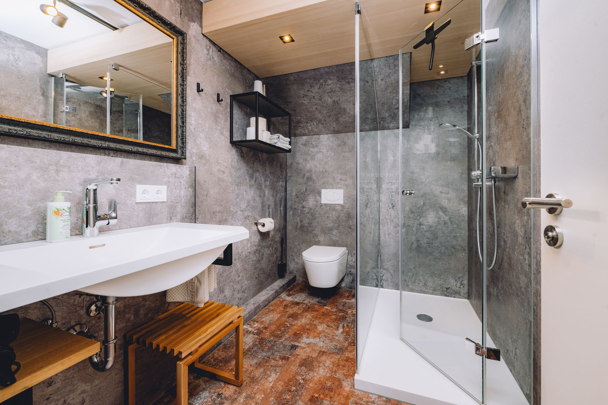 Ein modernes Badezimmer mit Steinwänden, schlankem Waschbecken, einem eingerahmten Spiegel und einer großen Dusche mit Glaswänden.