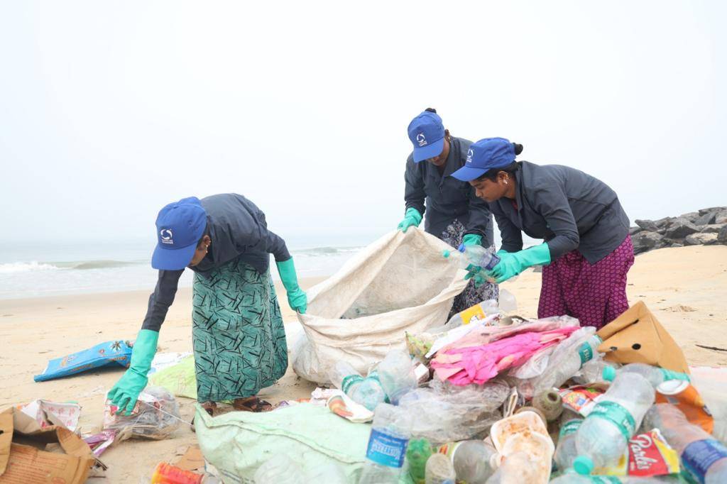 women picking up plastic from a beach 