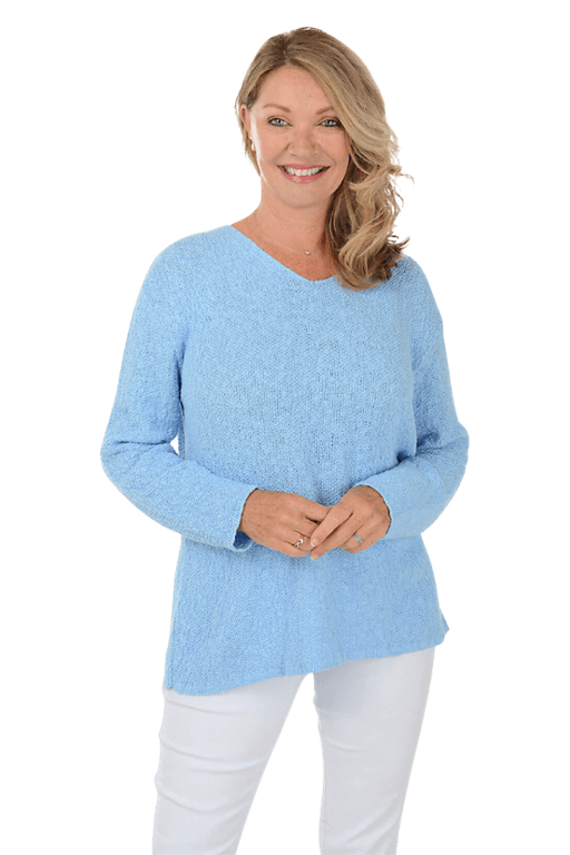 A woman wearing a light blue sweater and white pants