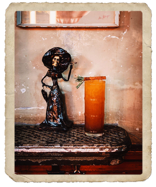 Prepared cocktail beside a miniature of a mexican Bruja.