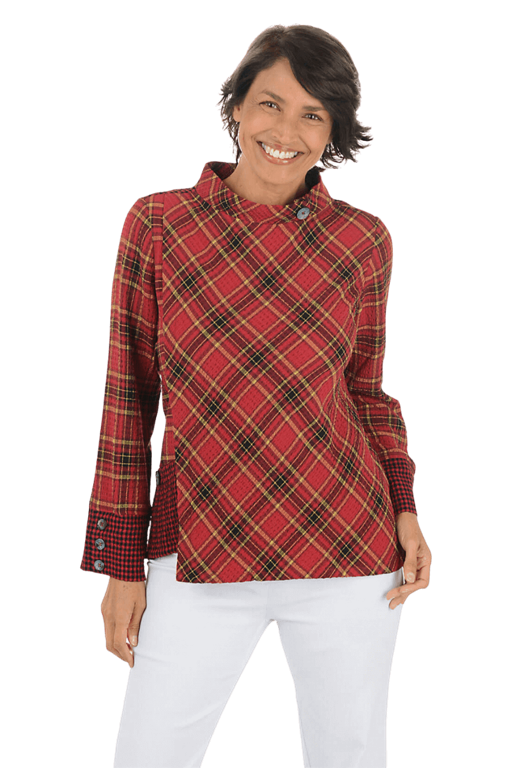 A woman wears a red plaid blouse and white pants against a beige background