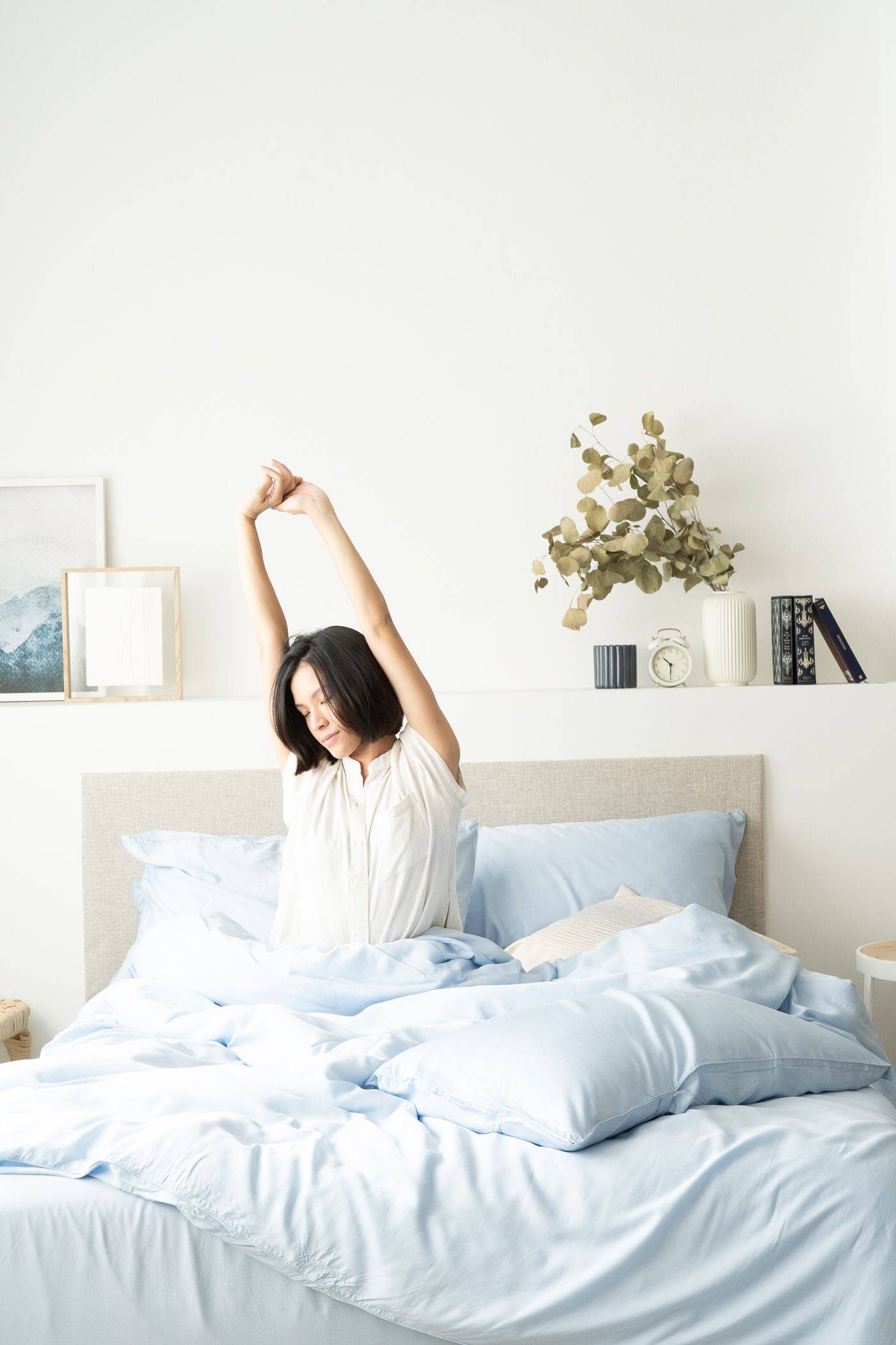 Girl stretching in bed, featuring Weavve's tencel lyocell bed sheet set with pillowcase in light blue