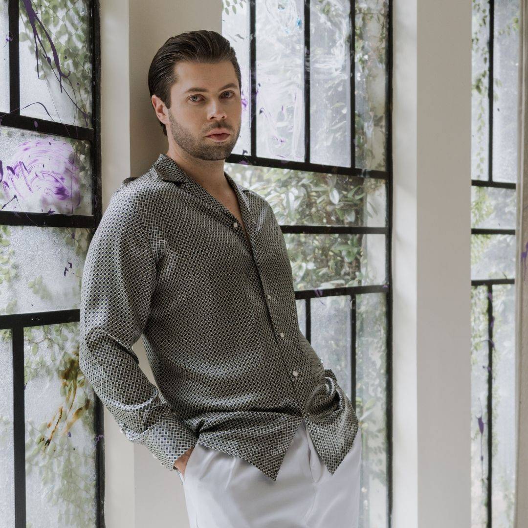 model leaning against the wall wearing a long sleeve blue green diamond silk shirt from 1000 kingdoms