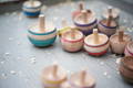 Colorful wooden spinning tops arranged on a table as simple open-ended toys for hands-on play and motor skill development