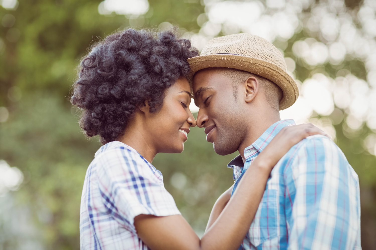 A young hip black couple with their eyes closed holding each other.