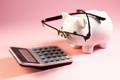 Petit cochon tirelire avec des lunettes regardant une calculatrice