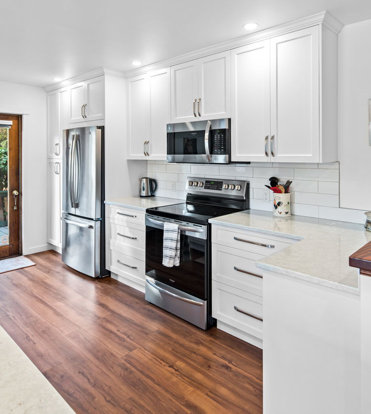 kitchen featuring natural light, refrigerator, electric range oven, microwave, light countertops, white cabinetry, and dark hardwood floors