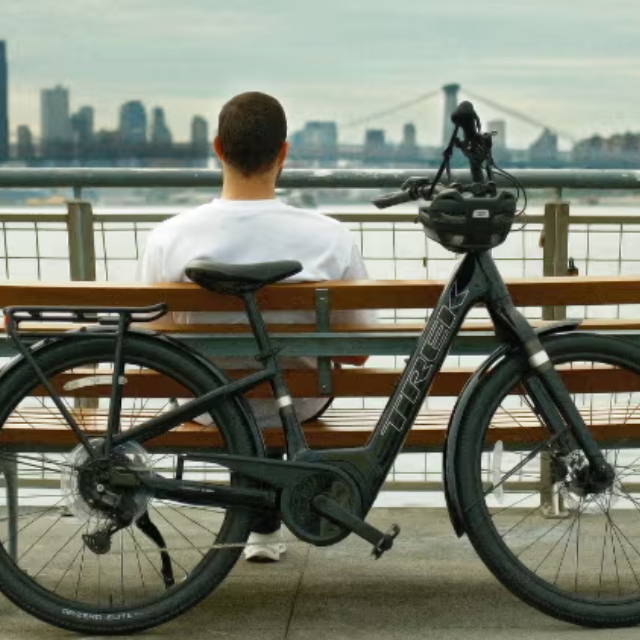 a man sitting on a bench overlooking the ocean behind his electric bike