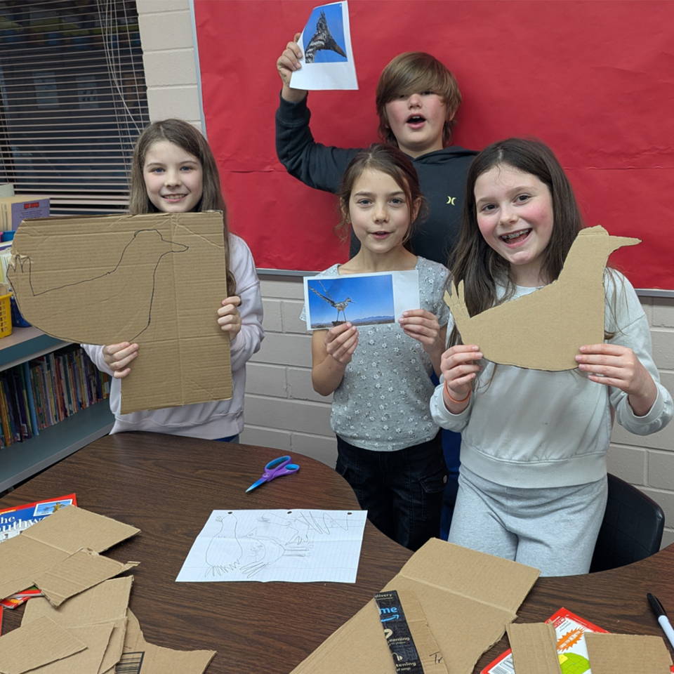 students cardboard templates held up