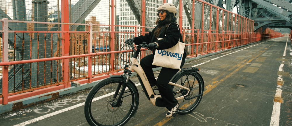 a woman riding an electric bike across a bridge in New York City