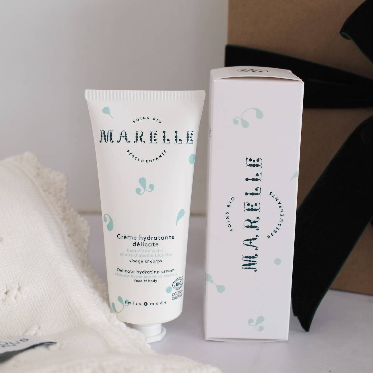 coffret cadeau bébé, couverture tricot bébé, crème hydratante bio, box naissance suisse, coffret bébé haut de gamme, couverture coton OEKO-TEX, soin bébé naturel, marques suisses bébé, fabrication suisse, cosmétique bio suisse, cadeau naissance original, produits bébé raffinés