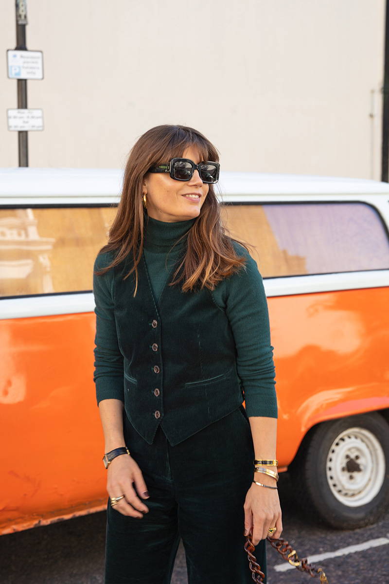 Sarah Corbett-Winder poses in front of a orange camper van wearing YOLKE's Corduroy Love Suit