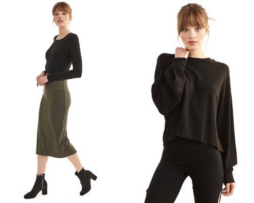 Woman wearing sustainable Groceries Apparel khaki green calf length jersey skirt with a black crew neck long sleeve top and woman wearing black leggings with cropped relaxed fit organic cotton sweatshirt