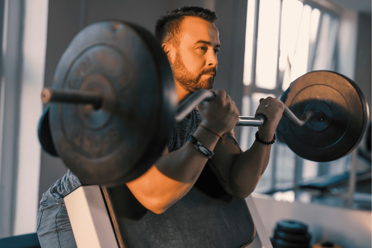 man lifting a barbell on the preacher curl bench man lifting a barbell on the preacher curl bench