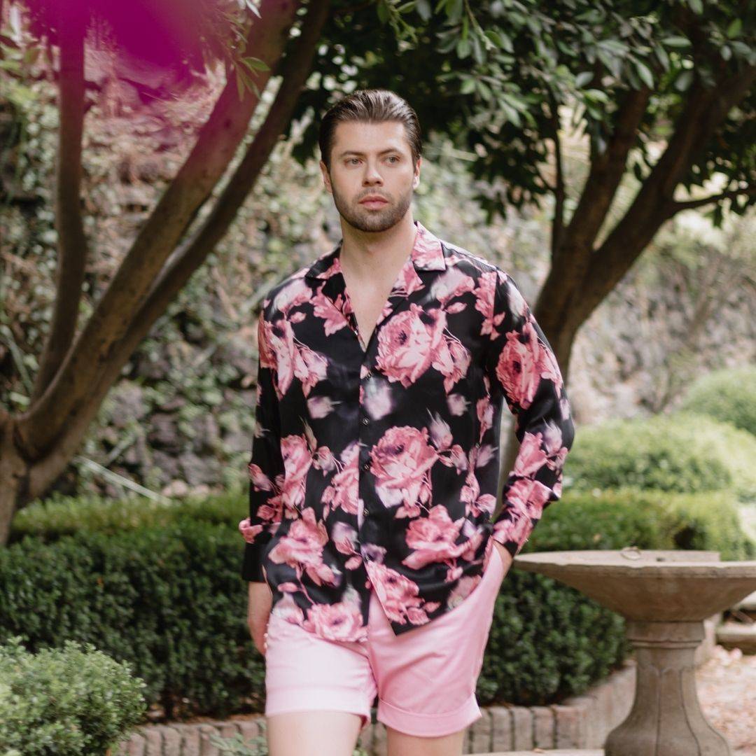 model walking outside wearing pink shorts and a long sleeve black and pink floral silk shirt from 1000 kingdoms