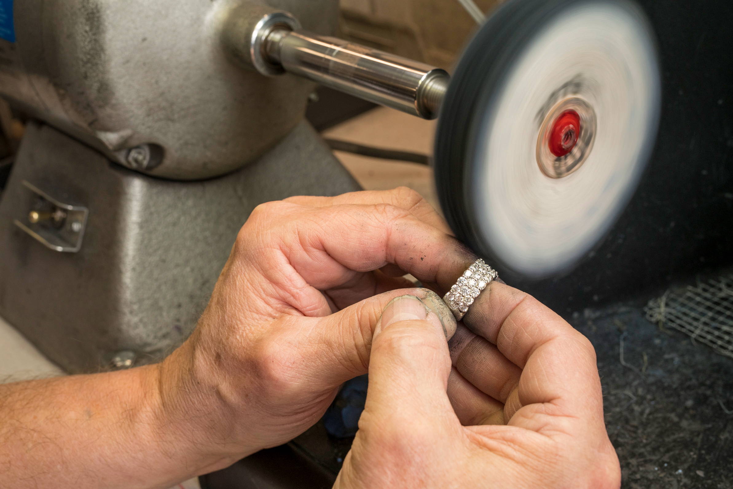 Jewelry polishing a diamond band on polishing wheel.