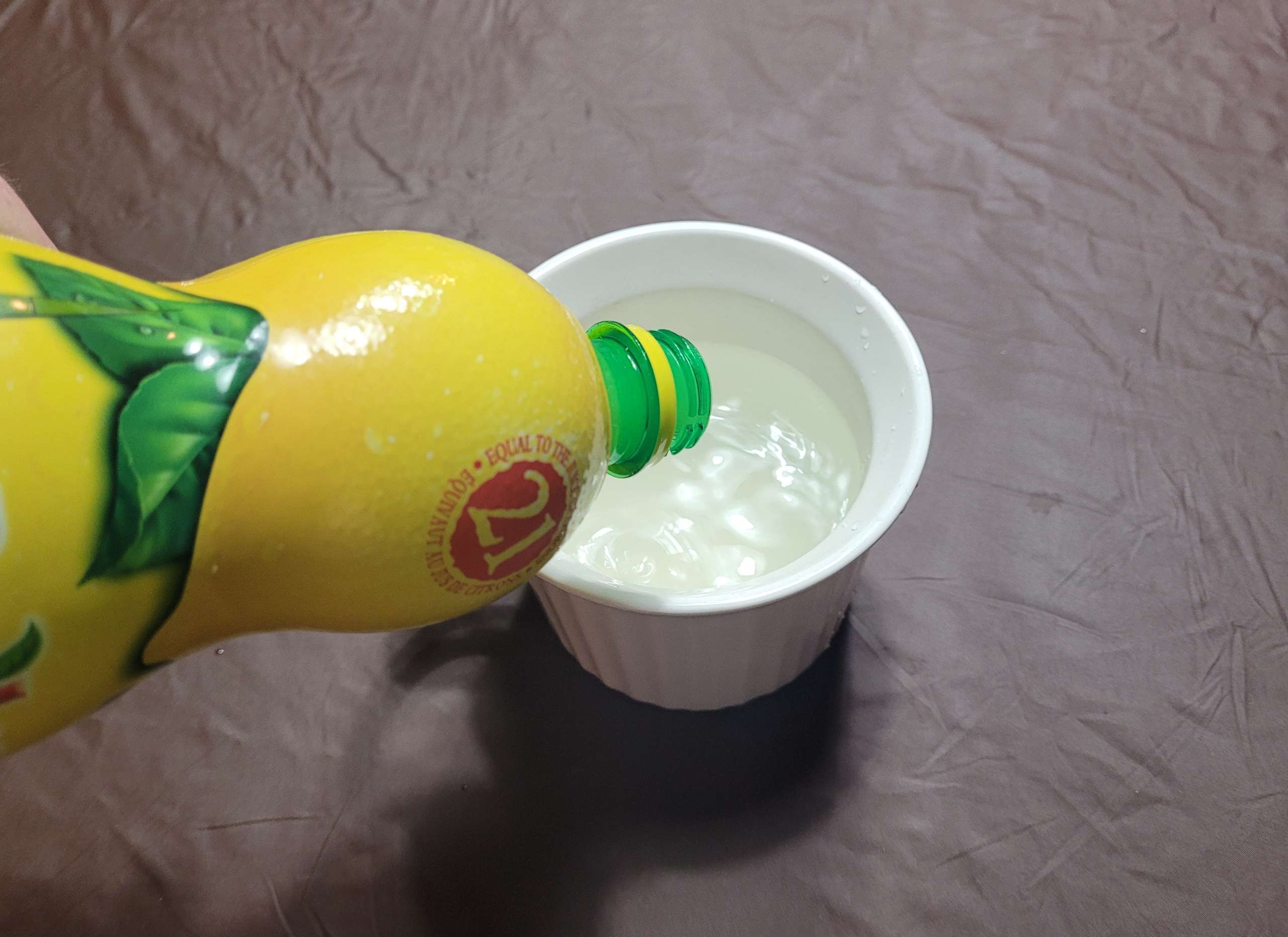 photo of lemon juice being poured into a bowl of lukewarm water
