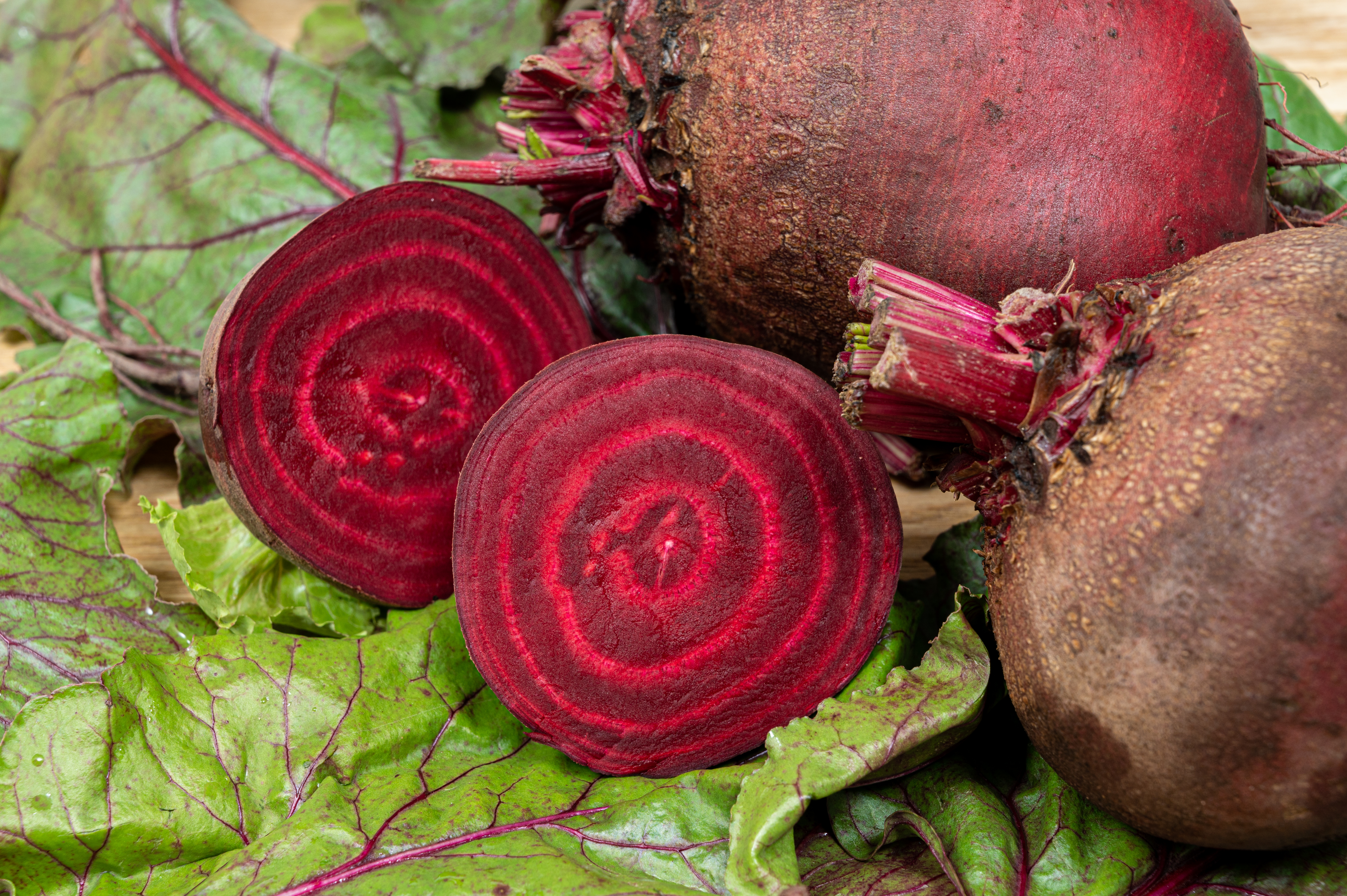 Beets and beet leaves with one beet sliced in half