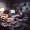 Desarrollador web sentado en su escritorio y abrumado por una cantidad enorme de papeles, proyectos, accesorios, etc...