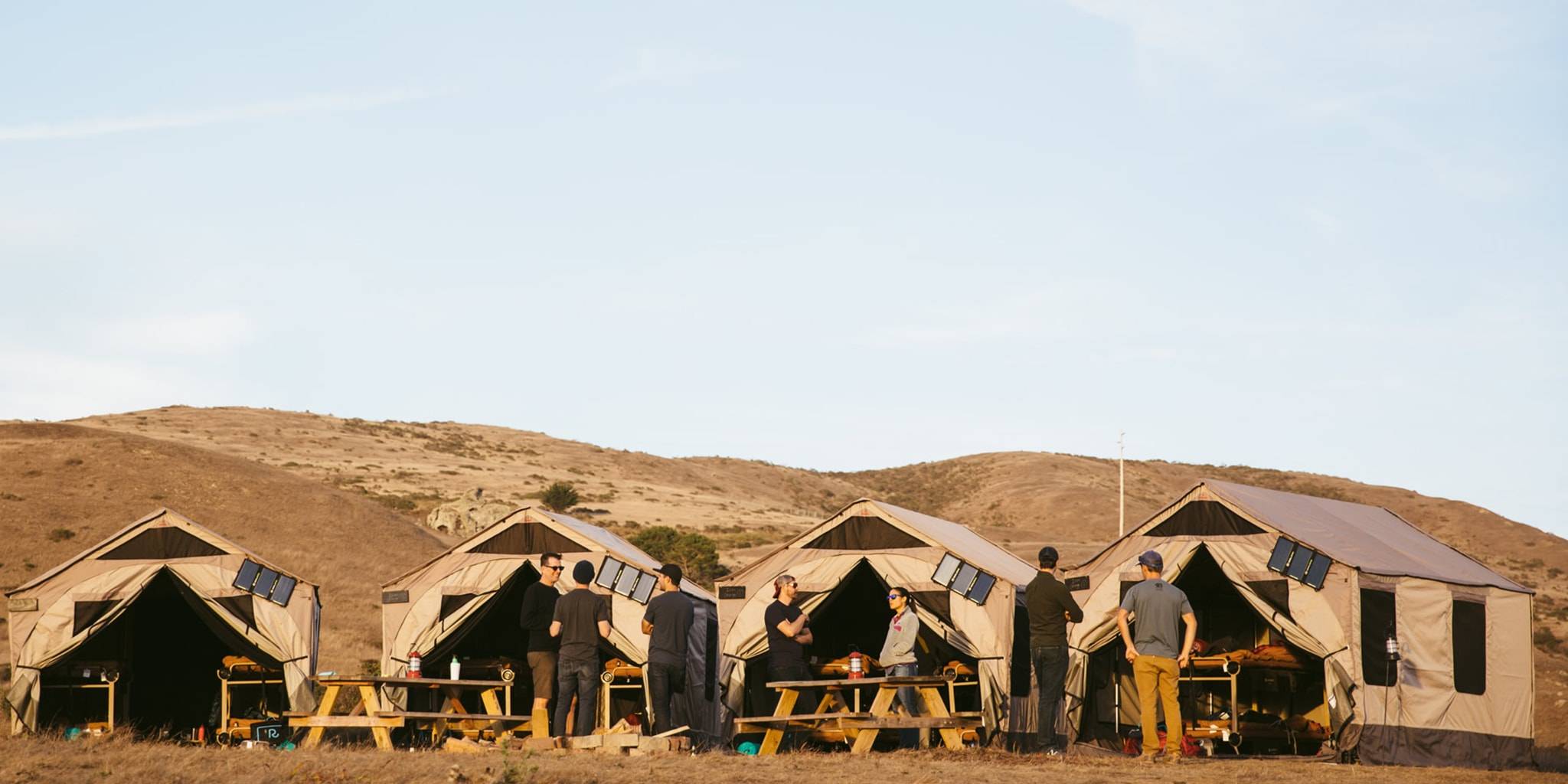 Four tents set up with picnic tables and Rumpl outdoor blankets