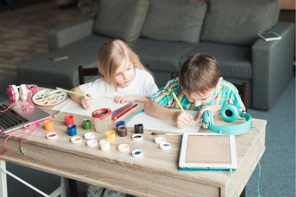 Brother and sister drawing on a sensory table.