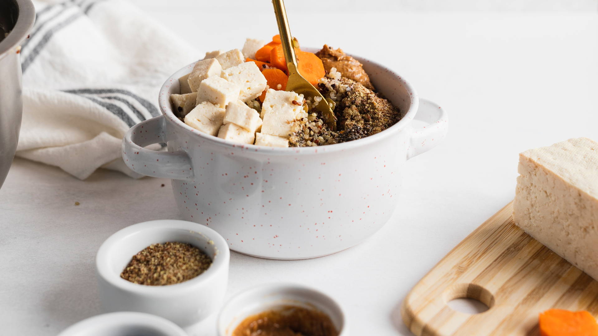 opal pets super greens and quinoa vegan dog food recipe in a white bowl with gold spoon in bowl and ingredients in smaller bowls
