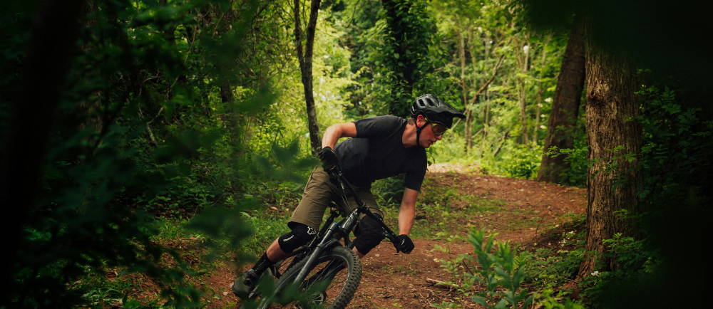 a man riding a mountain bike on a burm in the forest