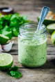 lime, cilantro, and garlic salad dressing in a glass jar with a spoon