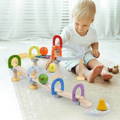Cute little boy sitting on a carpet and playing with Montessori Musical Marble Run set.