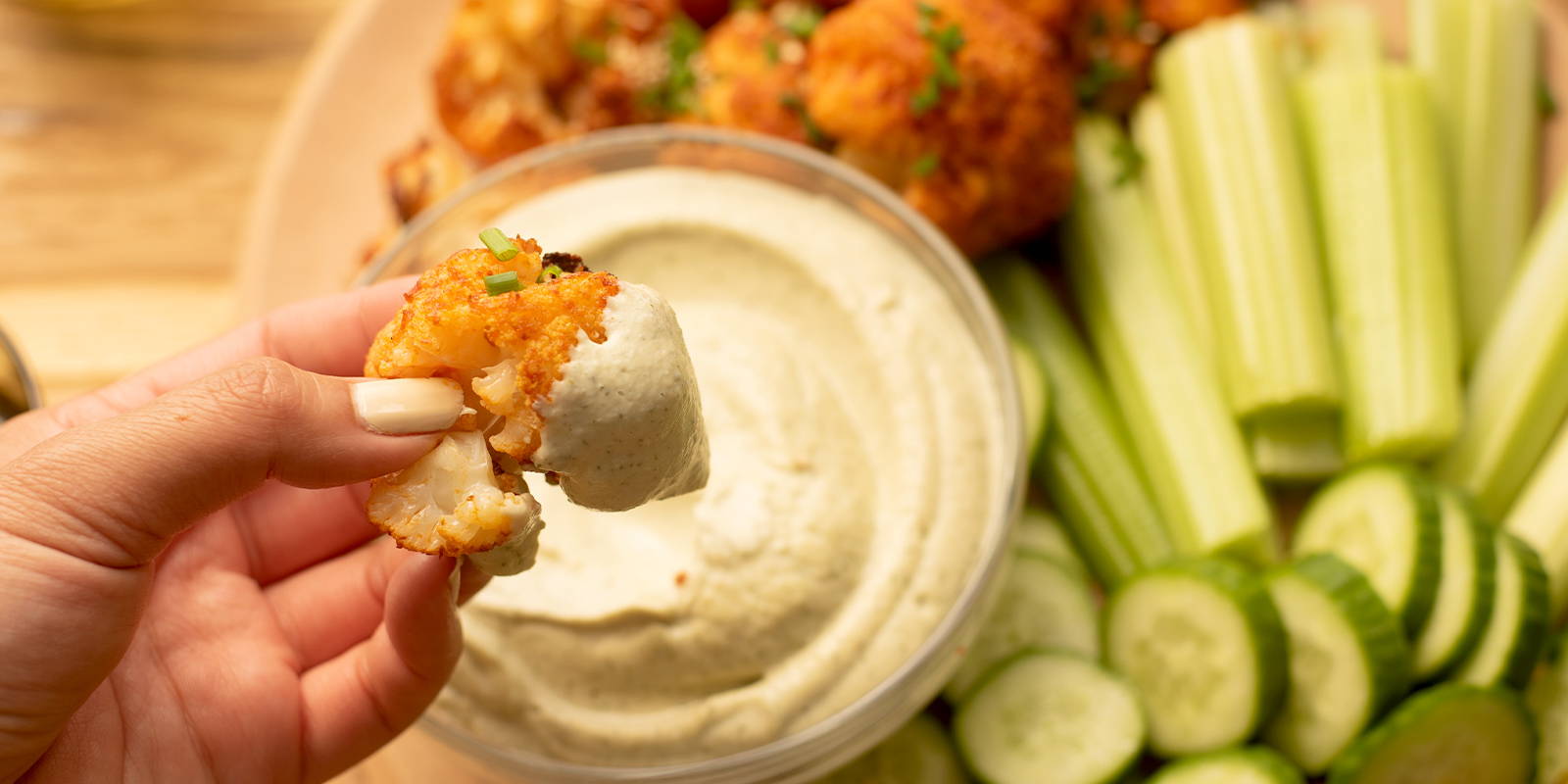 Buffalo cauliflower freshly dipped in cashew ranch over platter of appetizers.