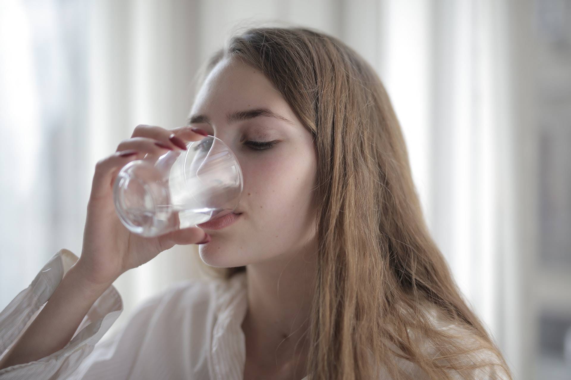 woman drinking clean water out of a glass
