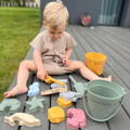 Toddler playing with the silicone beach toys on the porch.