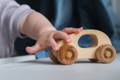 Child playing with a wooden car. 