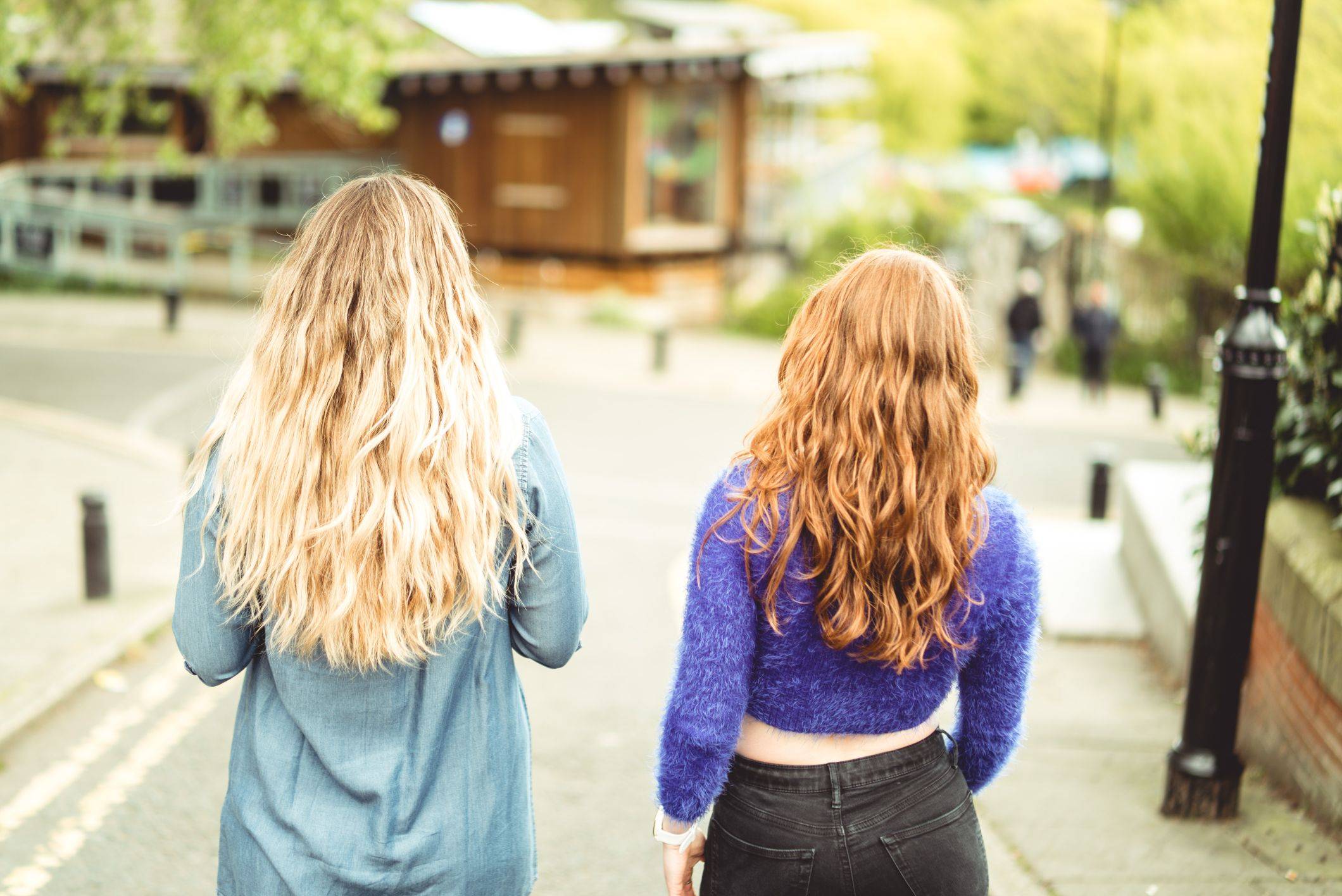 Image of two girls walking down road with their wavy hair on display