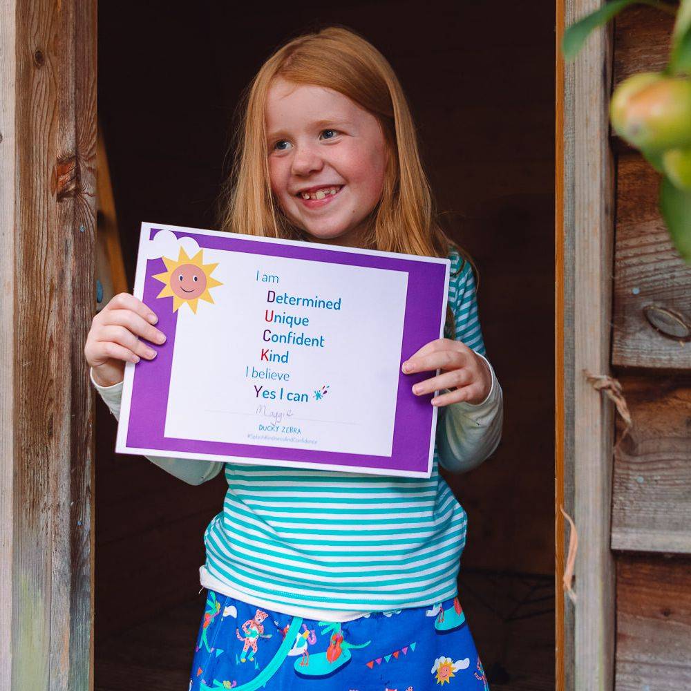 Image of a happy child holding a Ducky Zebra affirmation certificate