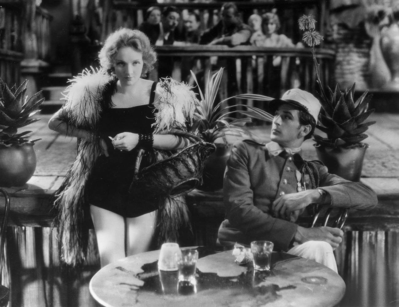 Marlene wearing a performance outfit revealing her legs, standing next to a soldier at a bar.