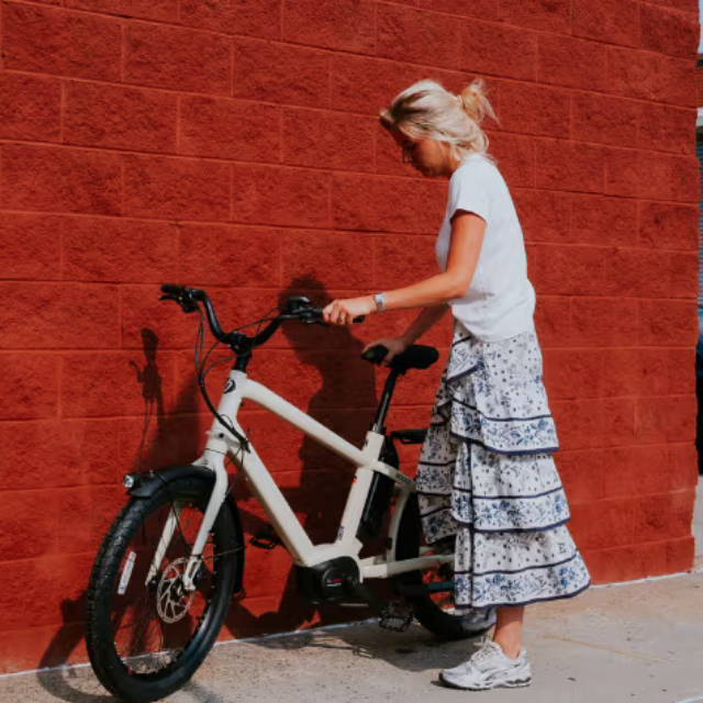 Rider standing next to Benno Boost electric bike next to red wall