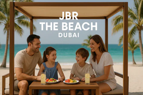 Happy family sits under a cabana on JBR beach in Dubai, enjoying drinks and fruit plates. Blue ocean and palm trees are in the background.