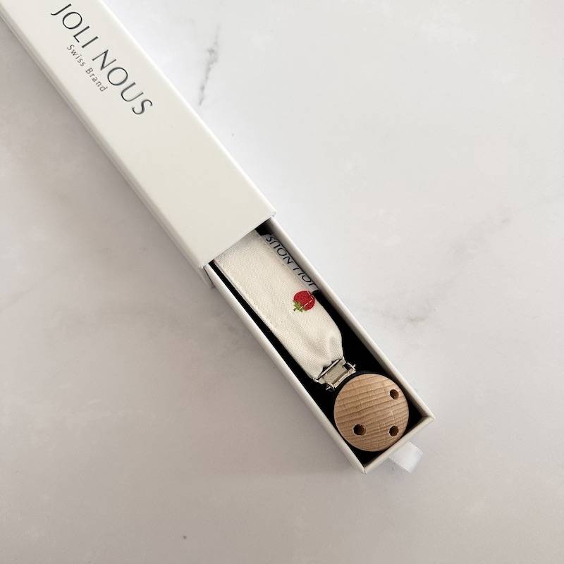 Attache-tétine fraises rouge blanc élégant de la marque suisse 'Joli Nous', un accessoire premium pour bébé, alliant design raffiné et qualité exceptionnelle