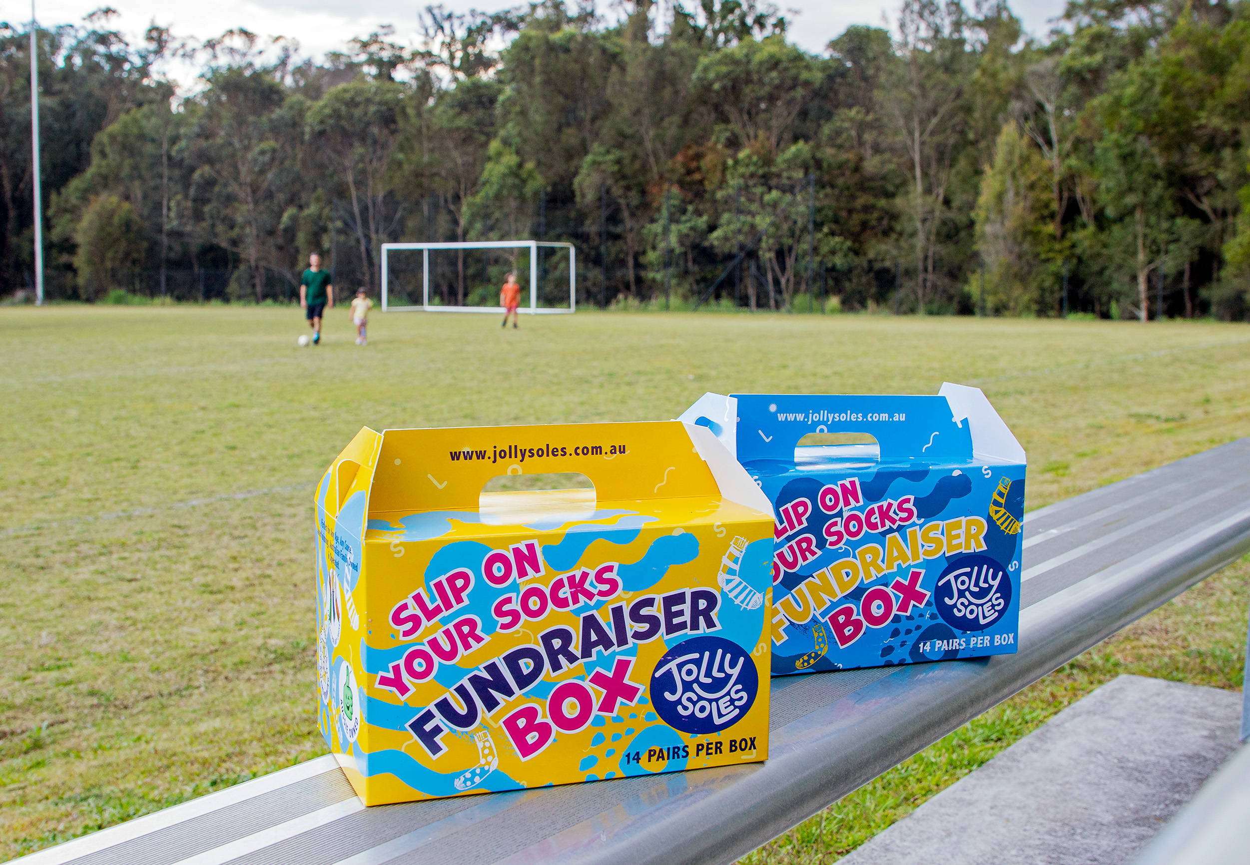 Jolly Soles creative fundraising boxes sitting on bleachers at a sports ground.