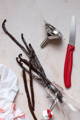 Vanilla beans sit in the top of an open bottle, surrounded by a paring knife and funnel