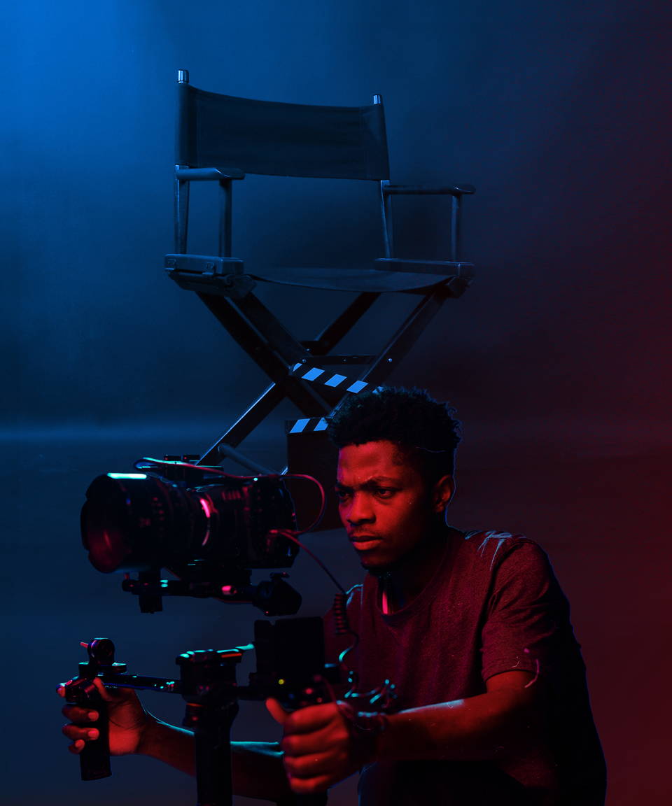 Black man filming a movie in dramatic lighting with a director's chair (small)