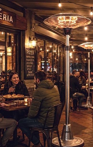 Calefactor de terraza de pie ANWO en un restobar con clientes compartiendo de noche