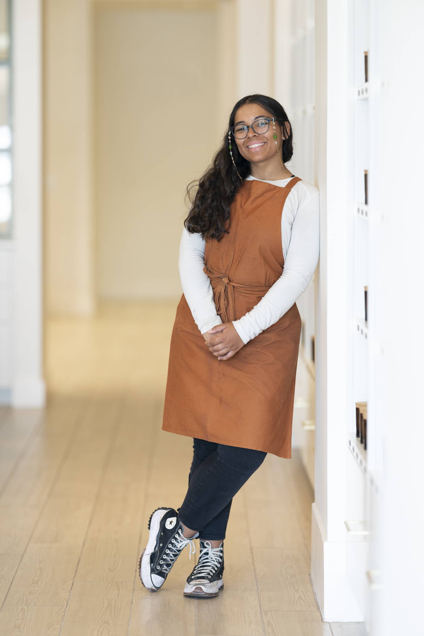 girl with glasses and orange apron standing 