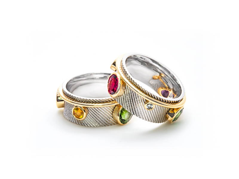 Two diagonally textured two-tone white gold or rose gold rings with ruby, peridot and citrine set in relief