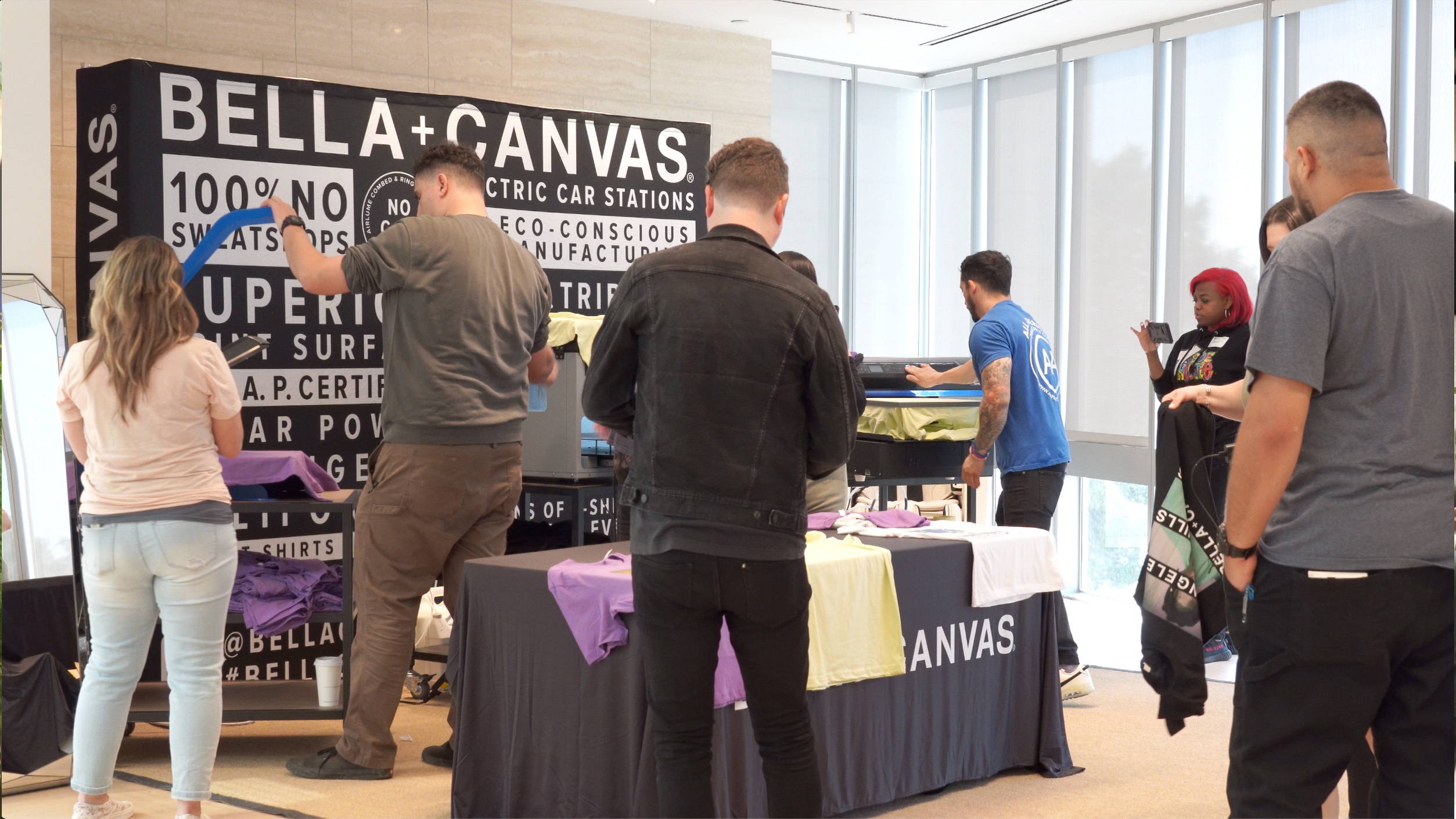 Attendees at the BELLA+CANVAS Creator Connect 2022 event watch Estevan Romero demonstrate the DTG printing process on the Epson F2100 printer.