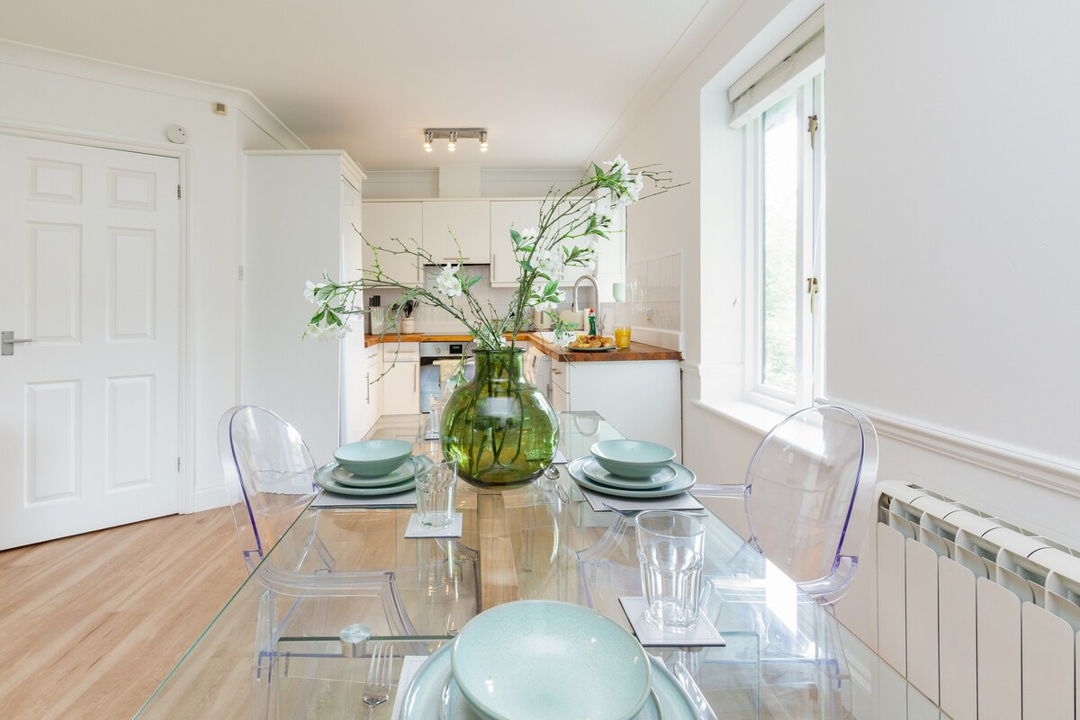Open plan kitchen and dining room with modern decor, clear table and flowers